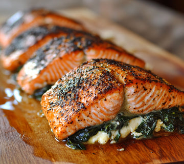 Blackened salmon seasoned with SwissAm Blackened, stuffed with creamy spinach and cheese, served on a wooden cutting board.